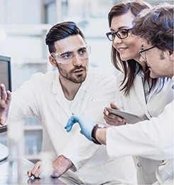 Accompagnement expert Chimie du végétal - ITERG Trois chercheurs en blouse blanche discutant dans un laboratoire - Chimie du Végétal ITERG
