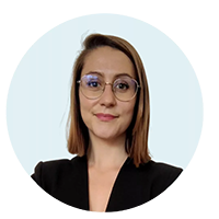 MARIANNE Portrait d’une femme aux cheveux mi-longs, portant des lunettes et un blazer noir, sur fond clair, en contexte professionnel.