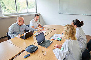 Réunion en salle de travail-ALLIANCE "Équipe en réunion autour d’une table, échangeant sur des documents et des projets scientifiques."