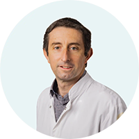 Portrait de Lionel Lagarde en blouse de laboratoire blanche, sur fond clair.