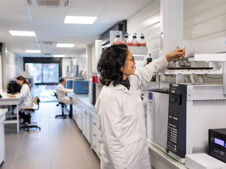  Technicien en blouse analysant des données chromatographiques sur ordinateur, à côté d’un système HPLC Thermo Scientific Ultima 3000.