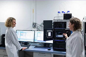  Deux chercheuses en blouse analysent des échantillons avec un appareil de chromatographie en laboratoire, dans le cadre de recherches en nutrition et santé.